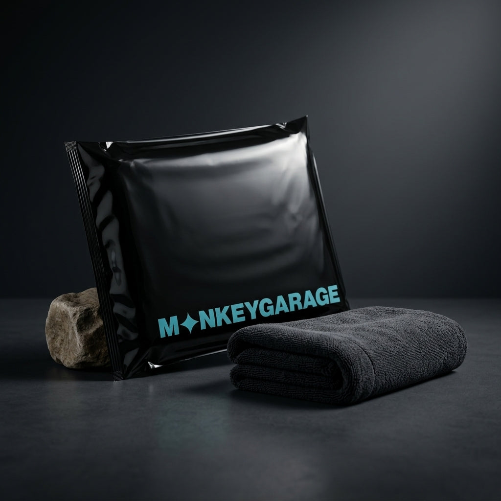 Black bag with 'MONKEYGARAGE' branding and a folded gray microfiber towel on a dark background, Hero image
