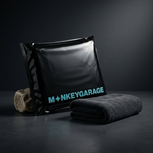 Black bag with 'MONKEYGARAGE' branding and a folded gray microfiber towel on a dark background, Hero image